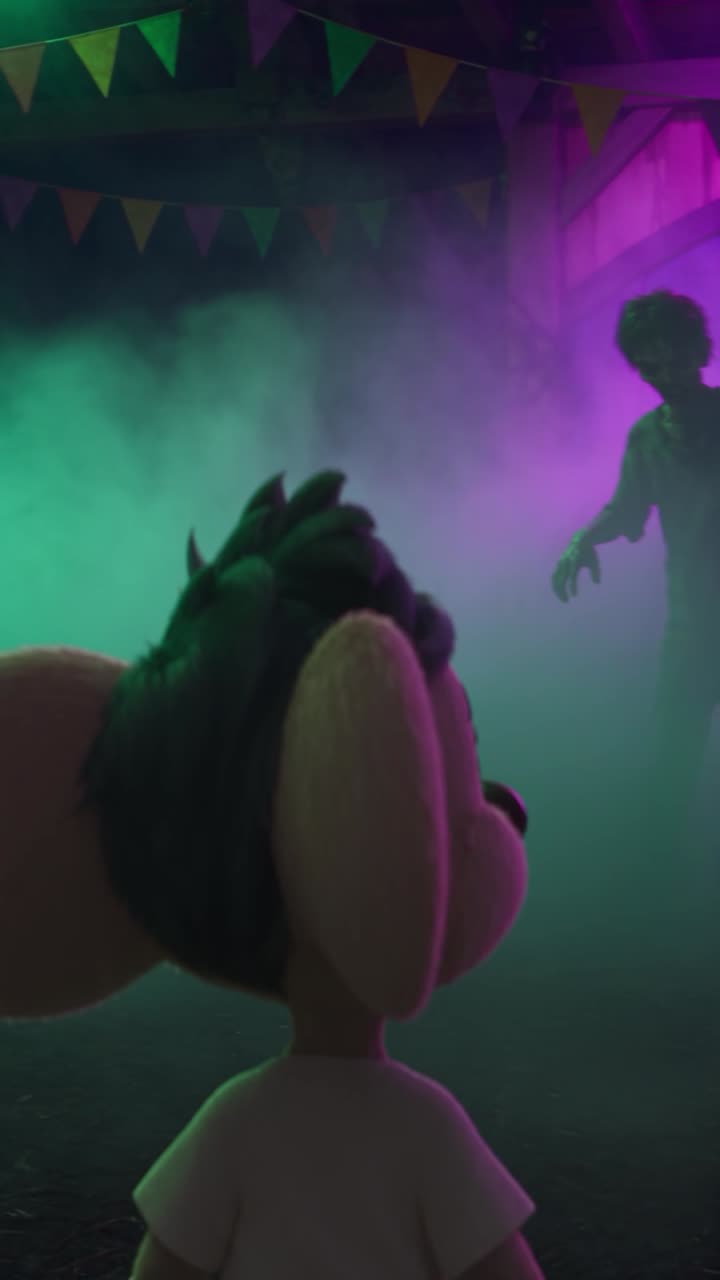 Ratello from behind facing a dark haunted ride lit green and purple